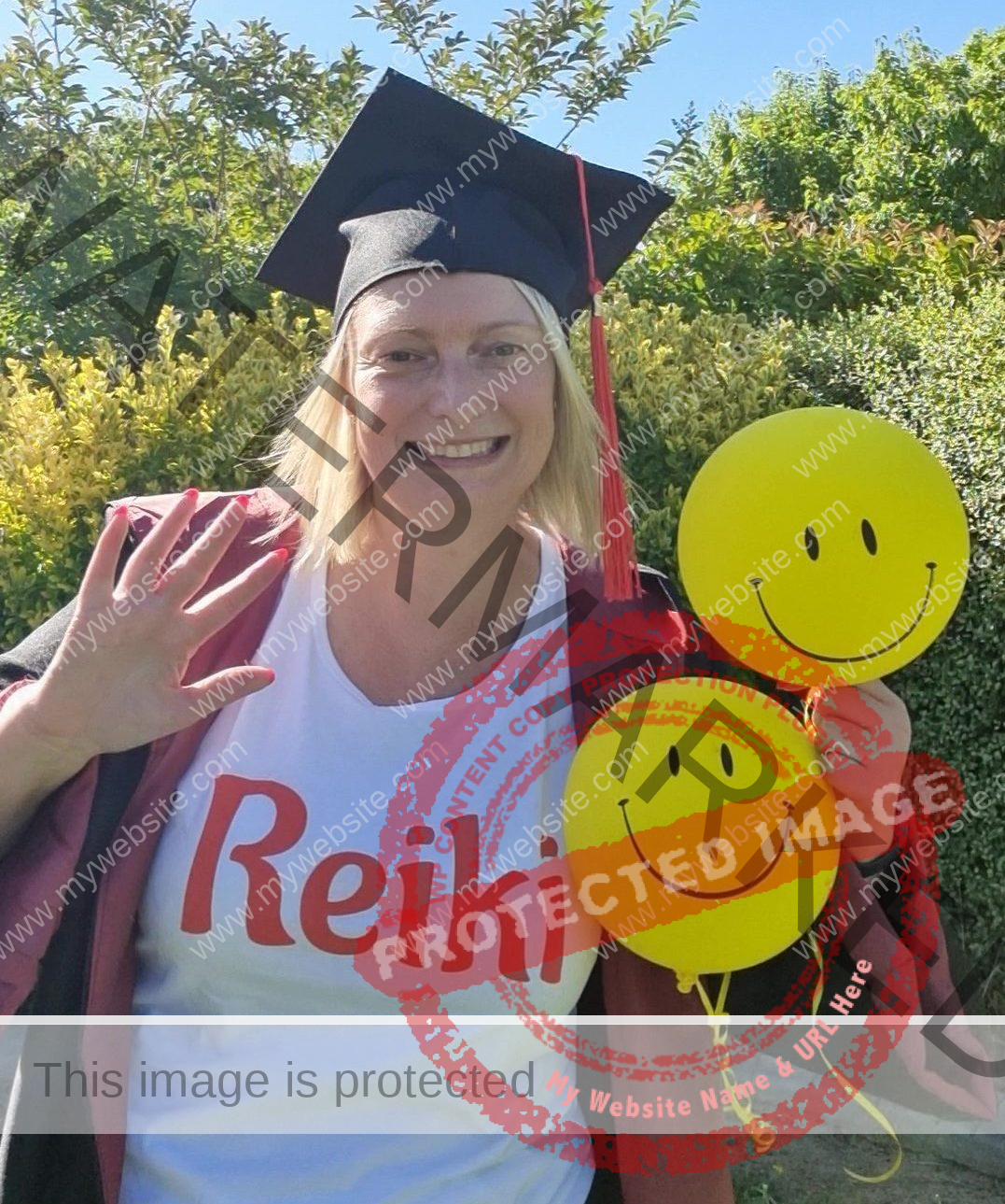 Reiki Level 3 training Reiki Master teacher in cap and gown holding 2 smiley balloons Reiki Level 3 training Reiki Master teacher in cap and gown holding 2 smiley balloons